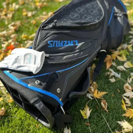 Premium black Lazrus golf bag with blue accents and white golf glove on grass with autumn leaves