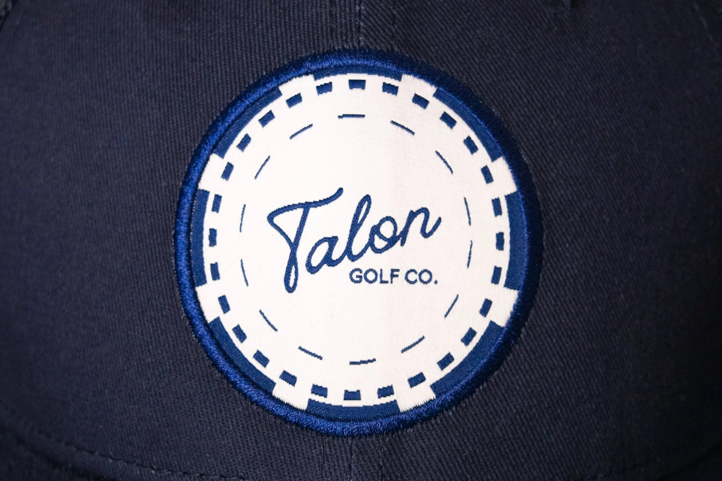 Navy blue trucker hat with a white and blue poker chip patch reading Talon Golf Co.