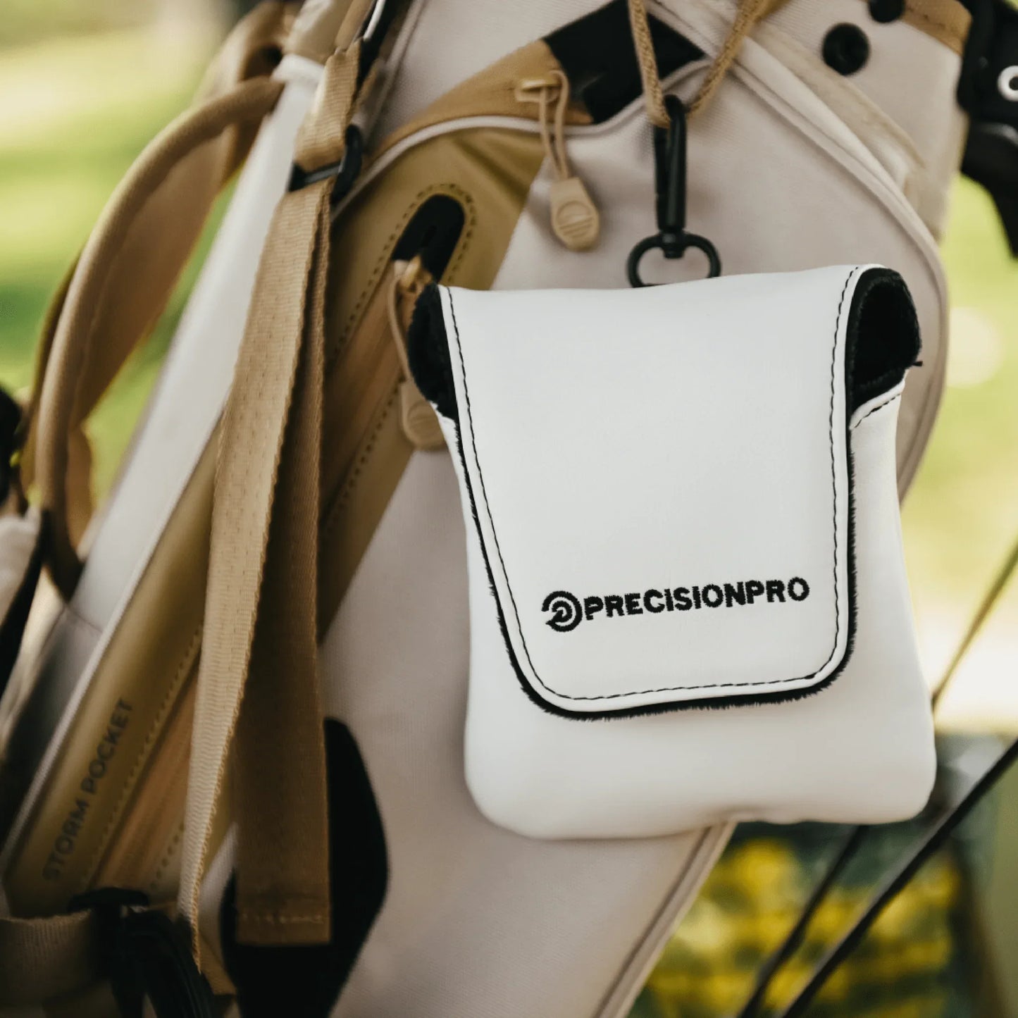 White PrecisionPro soft shell rangefinder case attached to beige golf bag with straps