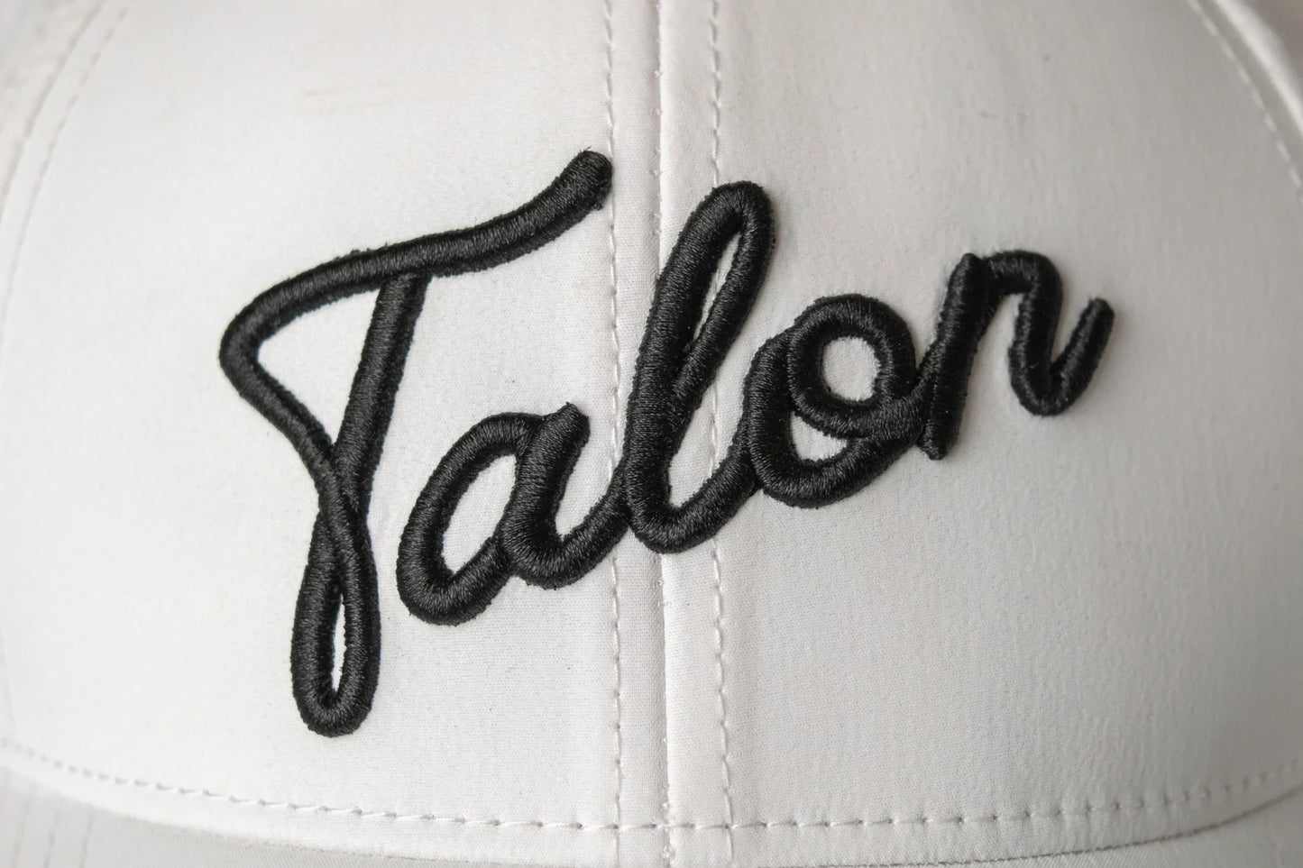 Close-up of white cap with black embroidered word 'Ralen' in script font