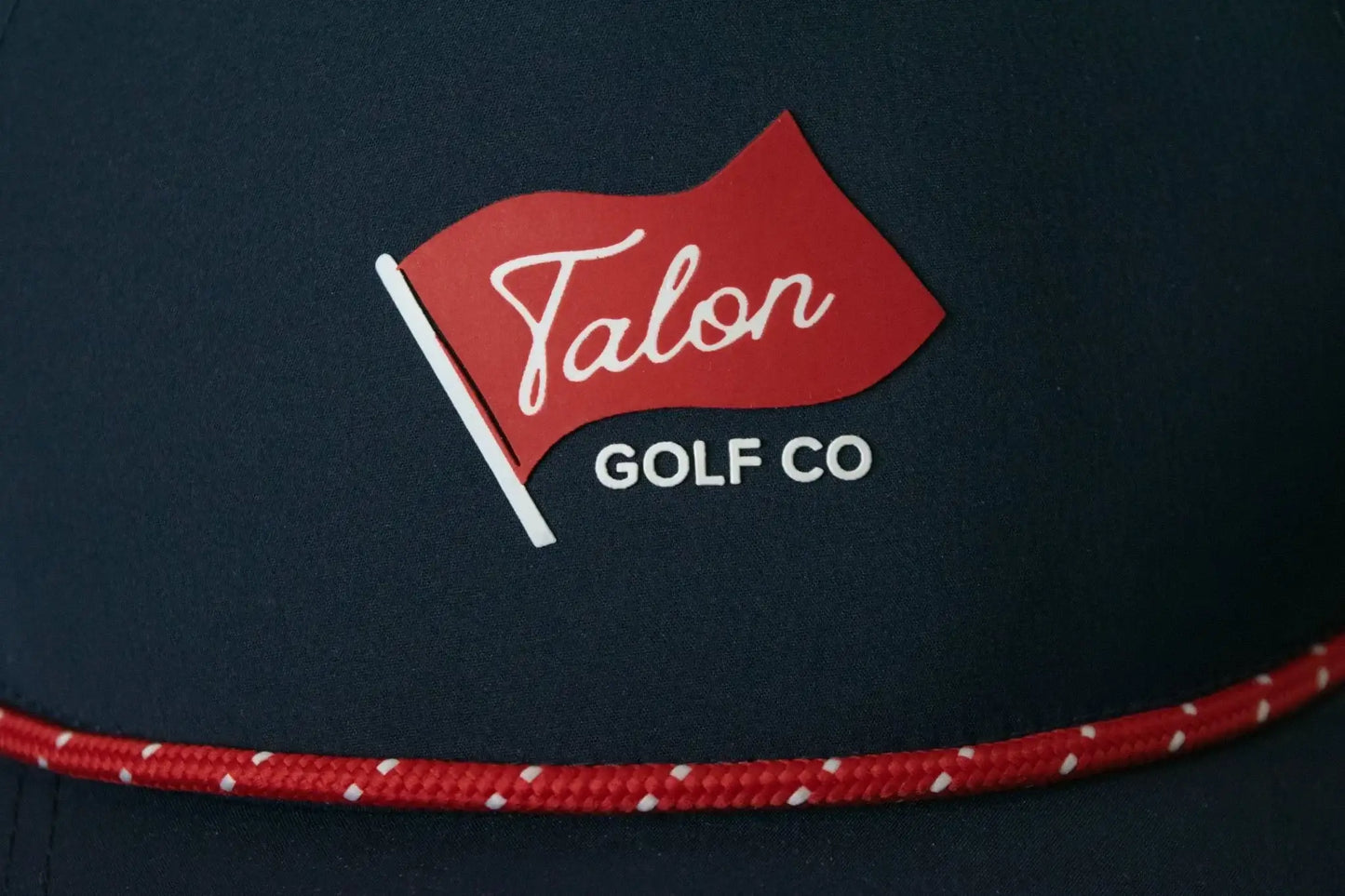 Navy blue baseball hat with red rope detail and red flag logo reading Talon Golf Co