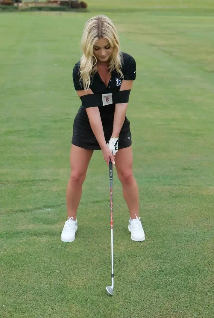 Woman practicing golf swing with figure 8 training strap on green golf course
