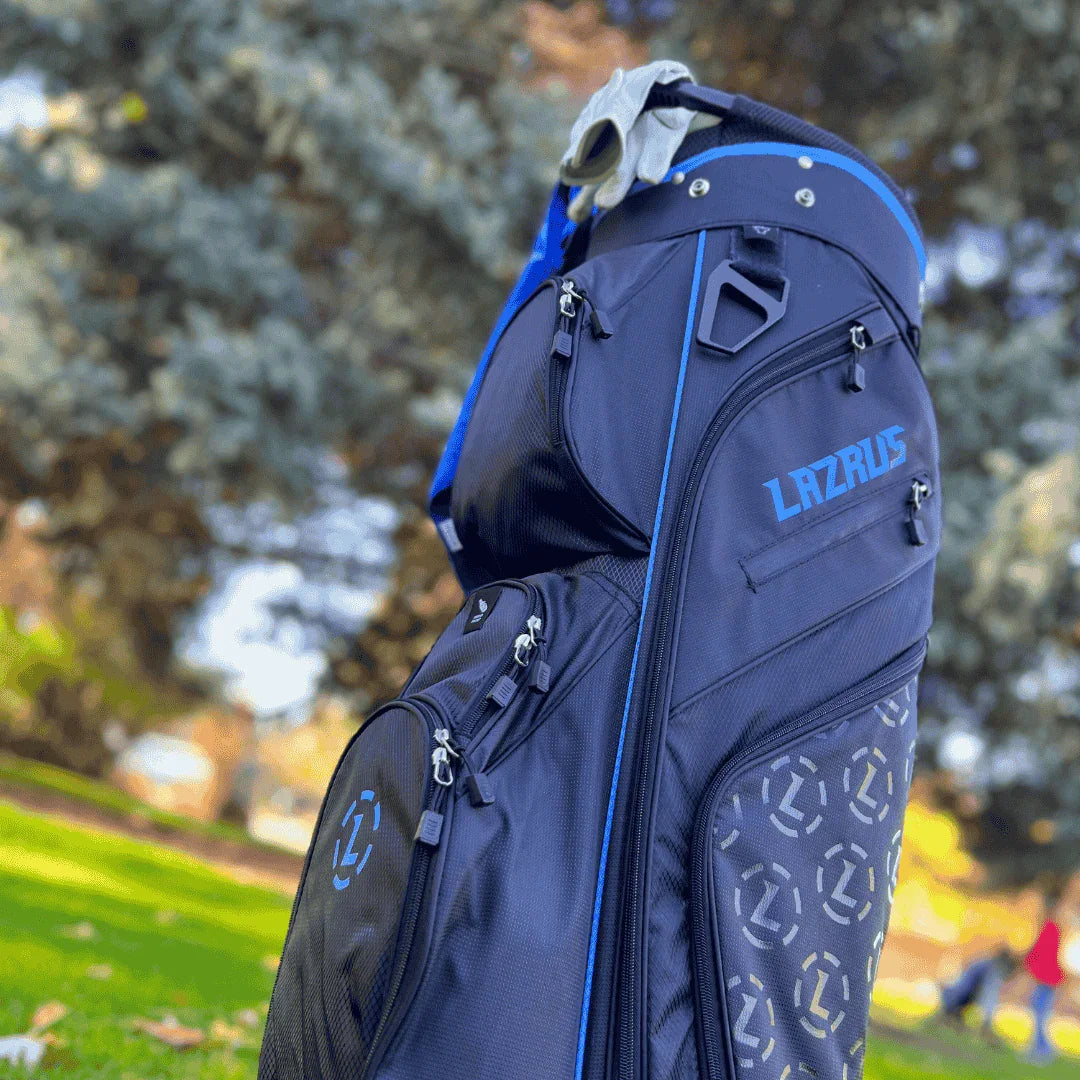 Black and blue Lazrus golf bag with multiple zippered compartments and golf gloves resting on top outdoors