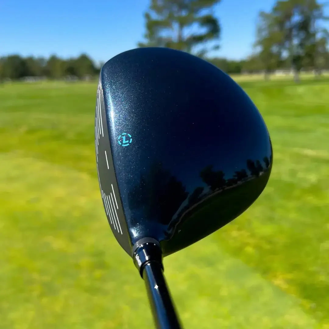 Black Lazrus golf driver club head with blue logo on a sunny golf course green