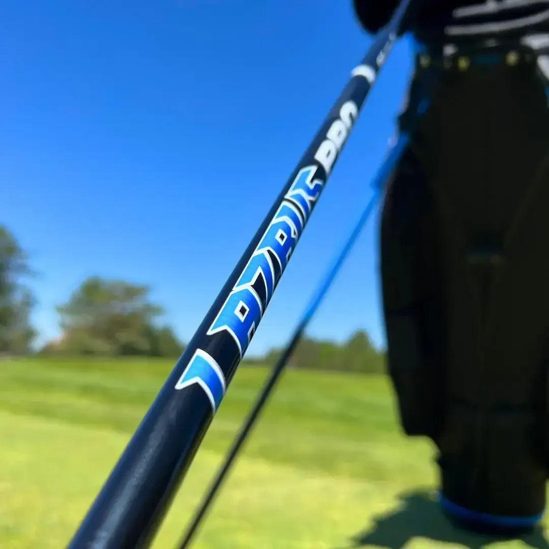 Close-up of golf club shaft labeled Lazrus DDN against green golf course and clear blue sky