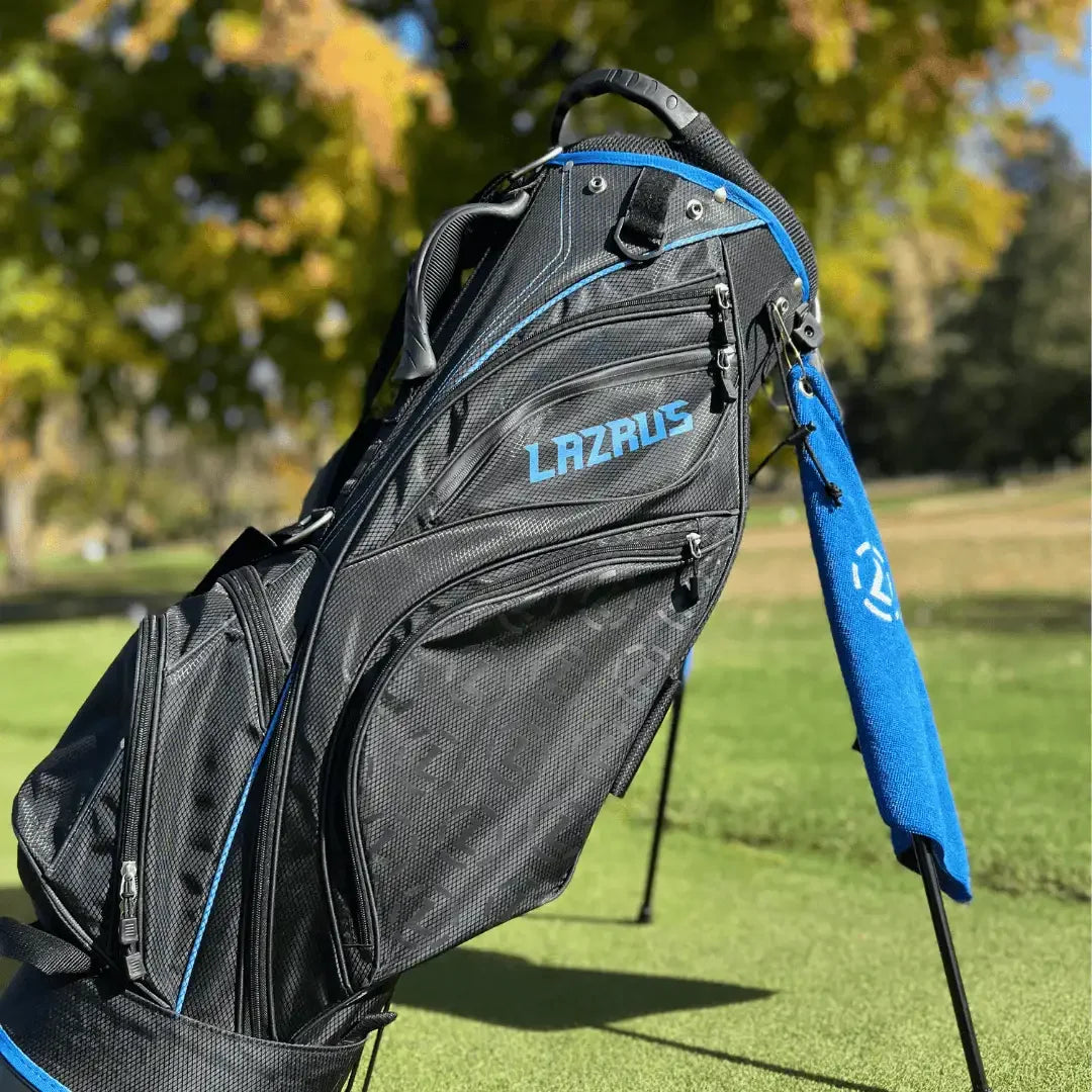 Black and blue Lazrus golf bag with stand, pockets, and towel on a golf course green