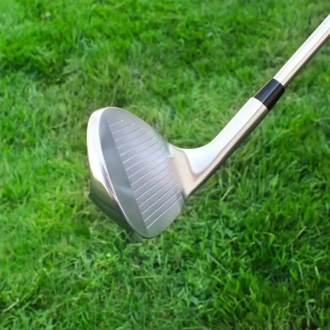 Close-up of shiny sand wedge golf club head with grooved face on grass background