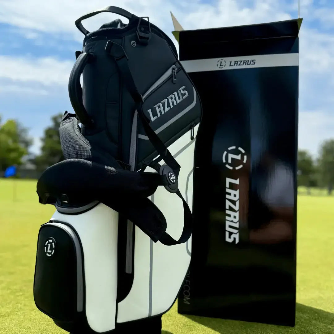 Black and white Lazrus golf bag and Lazrus branded box on grass under blue sky