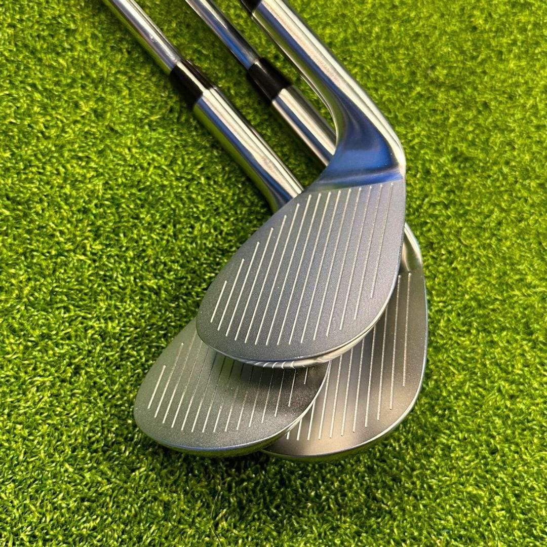 Set of three forged golf wedges with cavity backs on bright green artificial grass