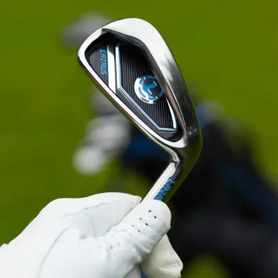 Close-up of a hand in a white golf glove holding a Lazrus branded golf iron with a blurred green background.