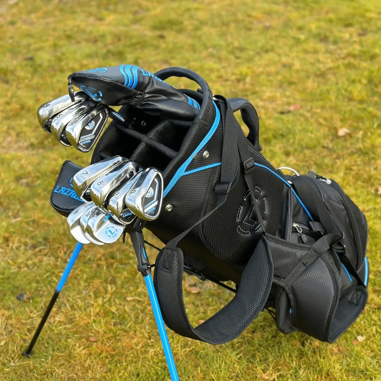Black and blue Lazrus premium golf bag with stand and steel irons on grass