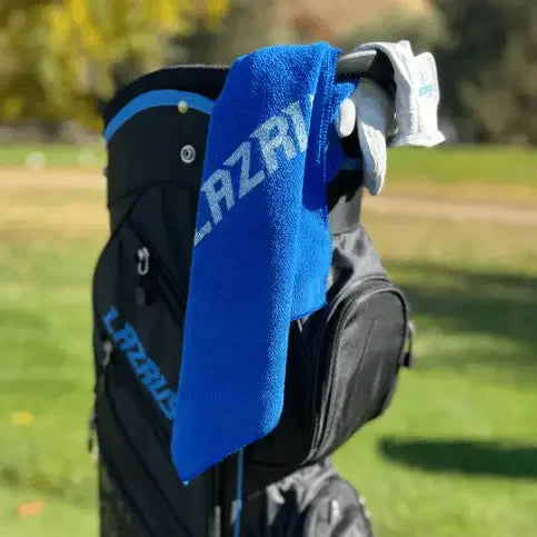 Black Lazrus golf bag with a blue Lazrus towel and white golf gloves on a sunny golf course
