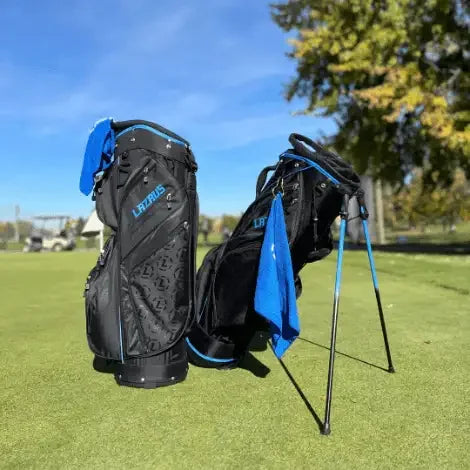 Two black Lazrus golf bags with blue accents on a green golf course under blue sky