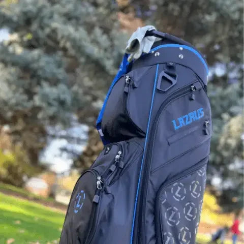 Lazrus black and blue premium golf bag with multiple zippered pockets and a golf glove on top in an outdoor park setting