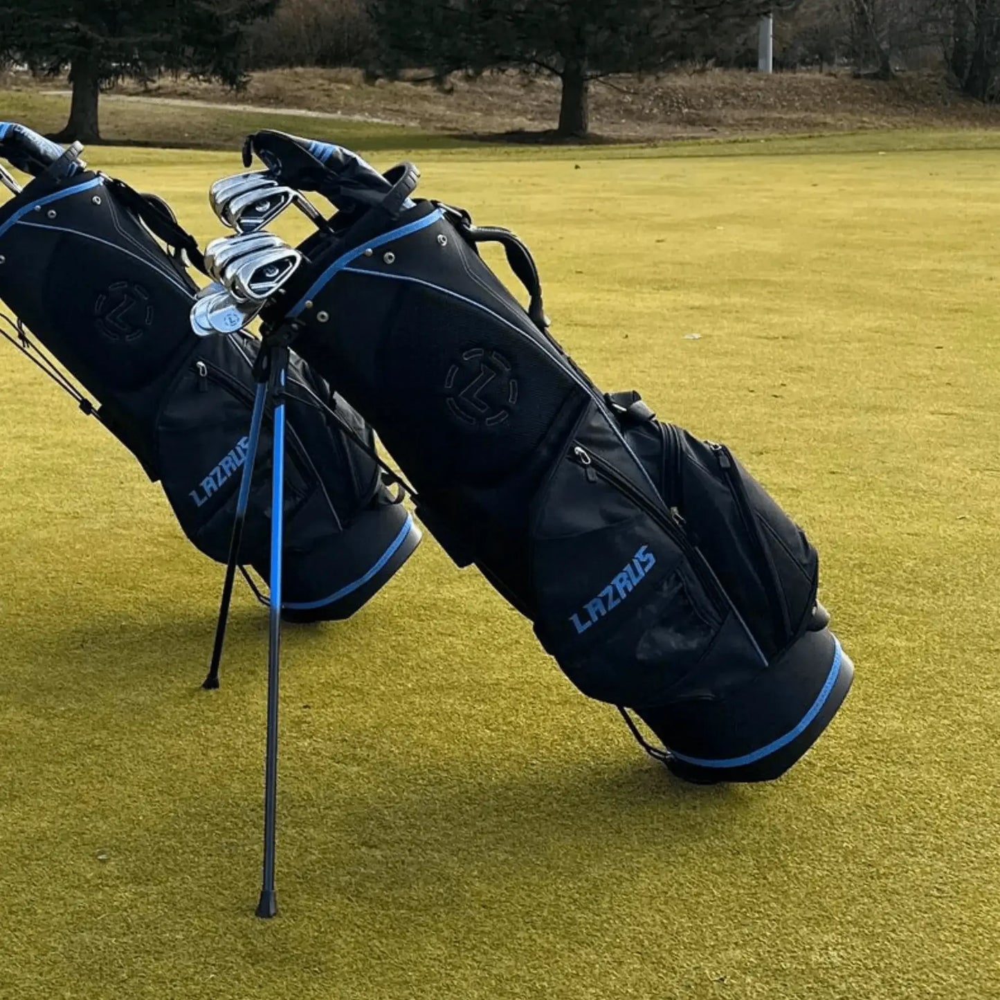 Two Lazrus black and blue premium golf bags standing on a golf course with clubs inside