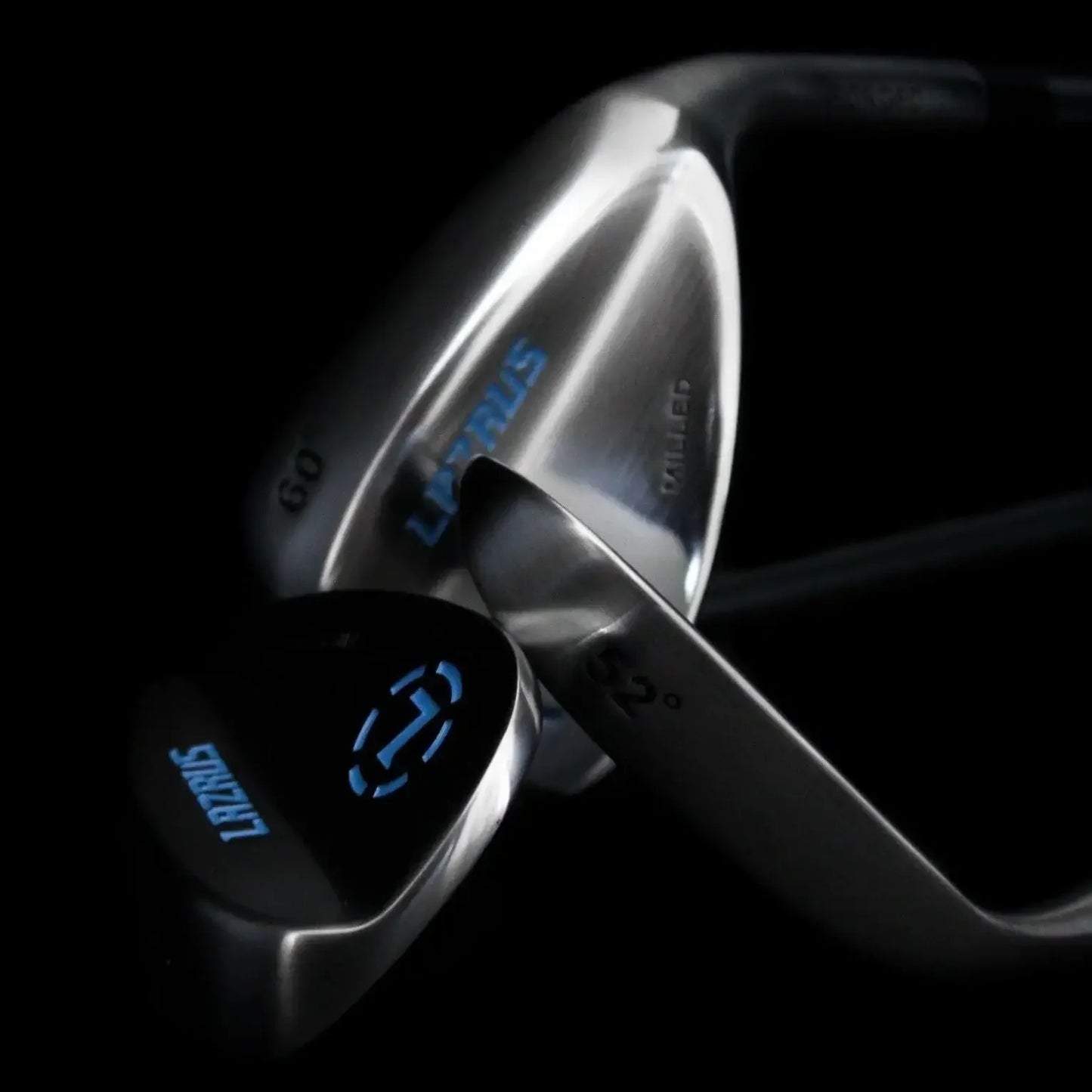 Close-up of Lazrus forged golf wedges with blue branding on a black background