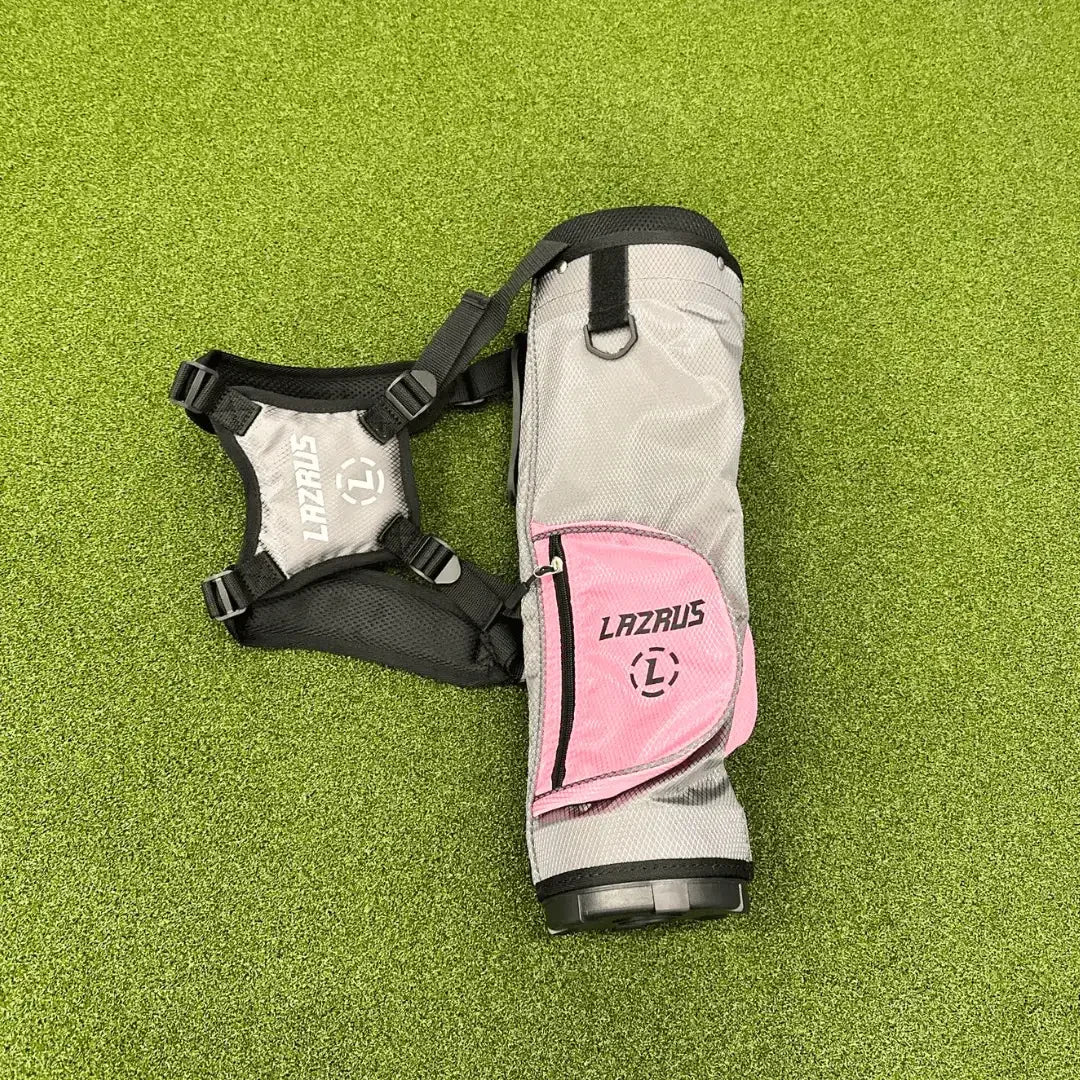 Gray and pink Lazrus junior golf bag with shoulder straps on green turf