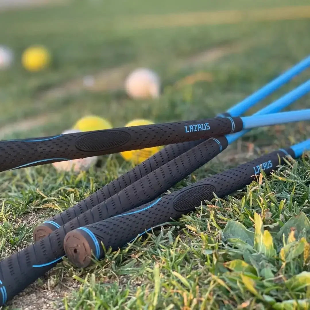 Close-up of Lazrus branded junior golf clubs with blue shafts on grass, golf balls blurred in background