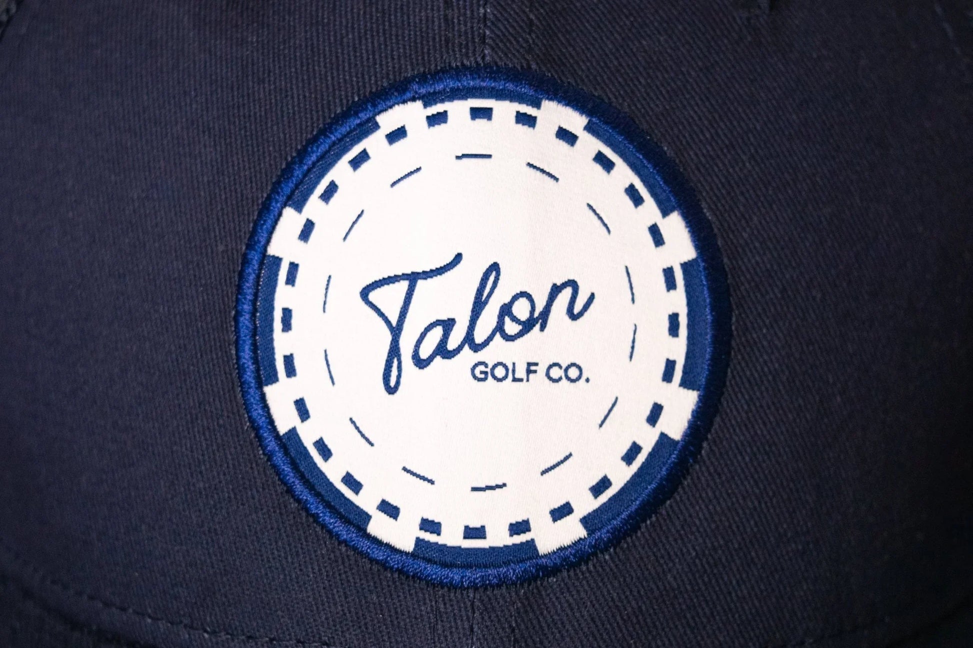 Navy blue trucker hat with a white and blue poker chip patch reading Talon Golf Co.