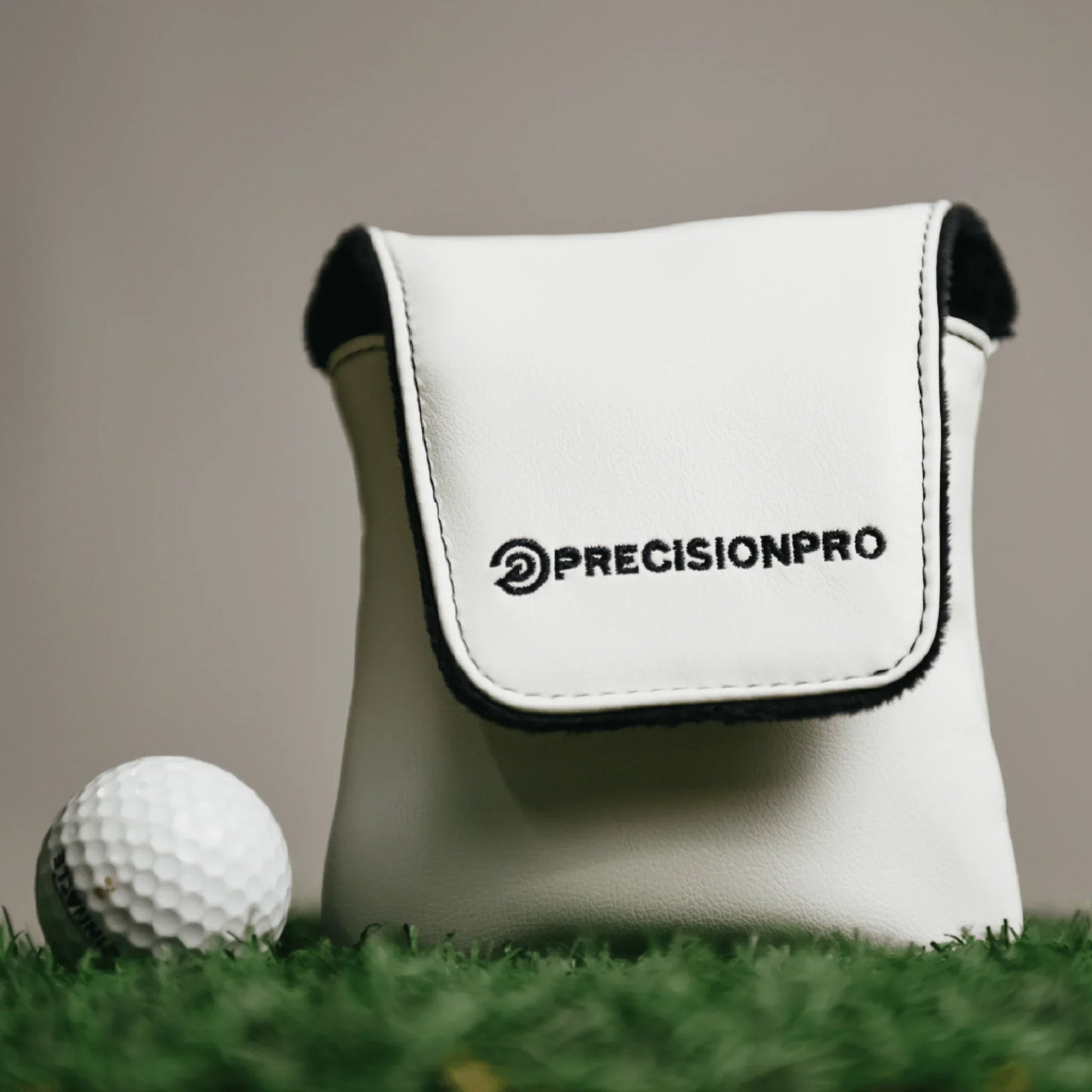 White PrecisionPro soft shell golf rangefinder case on green grass with golf ball