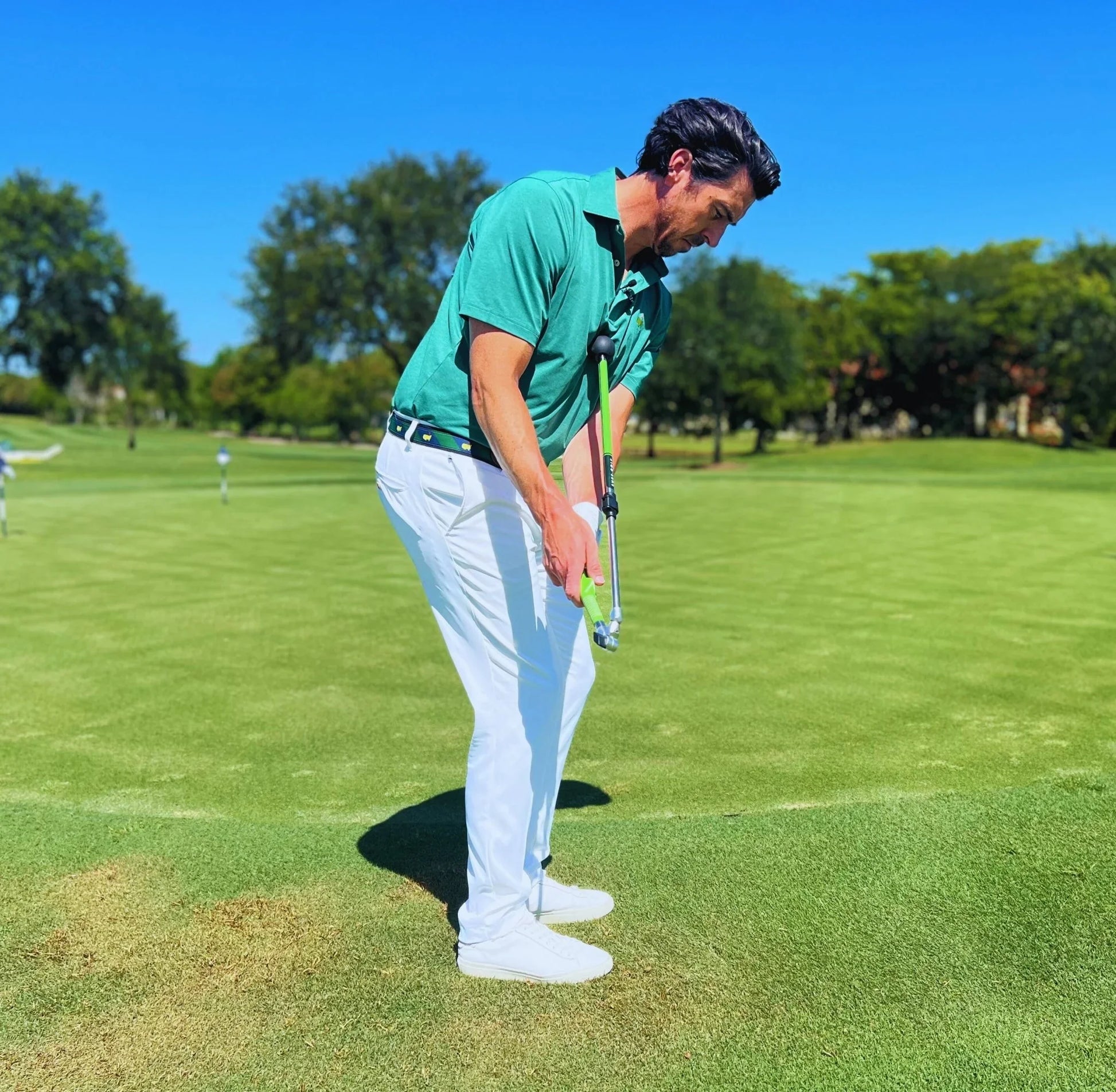 Man on golf course practicing putting with Sure Strike training aid and golf club
