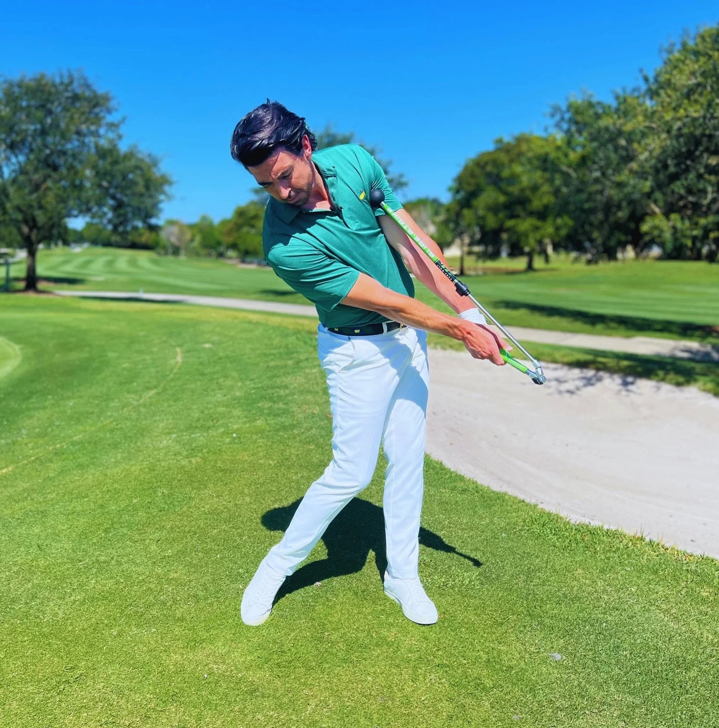 Man practicing golf swing using Sure Strike training aid on sunny golf course