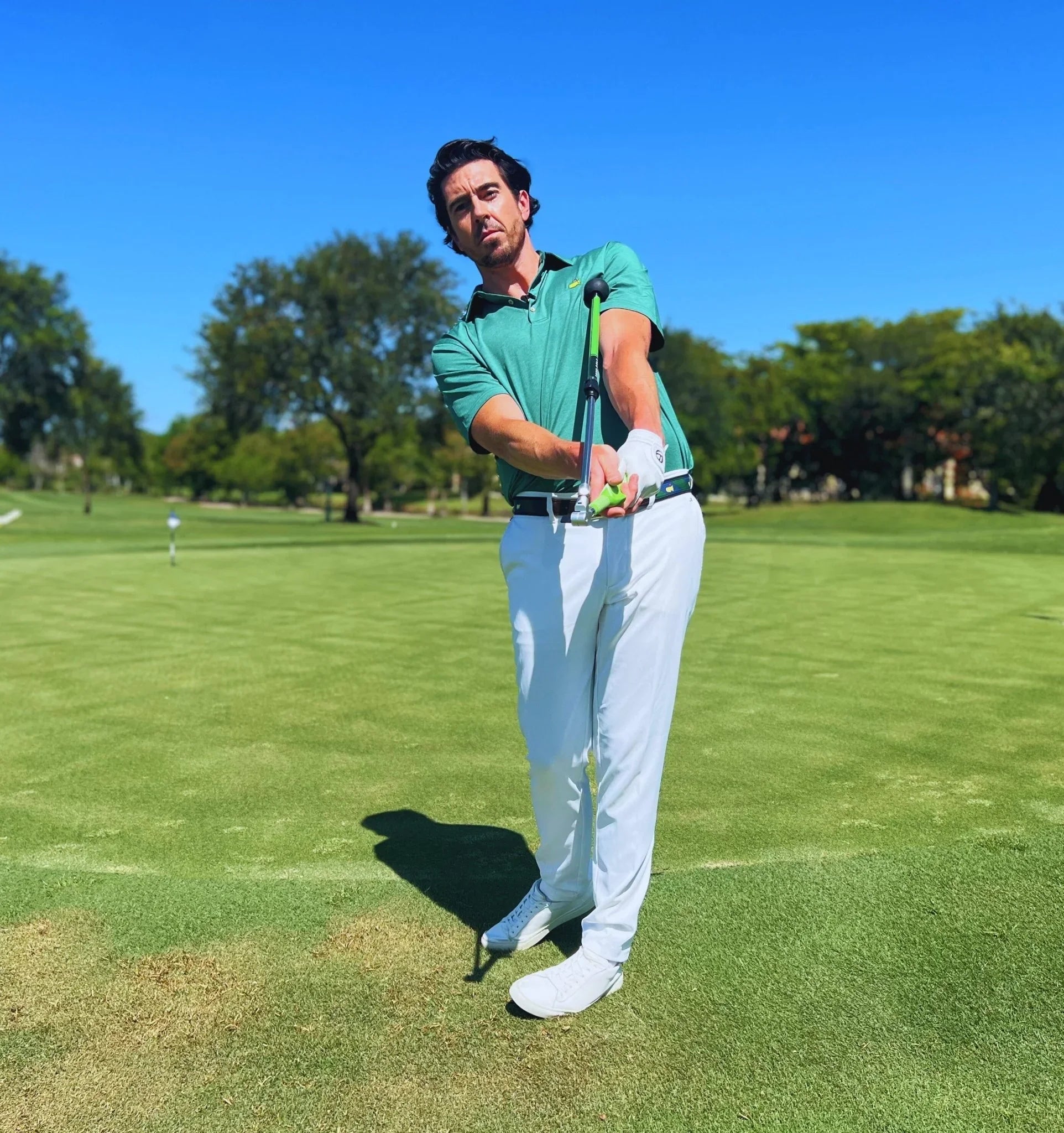 Man on golf course using Sure Strike golf swing training aid in sunny outdoor setting