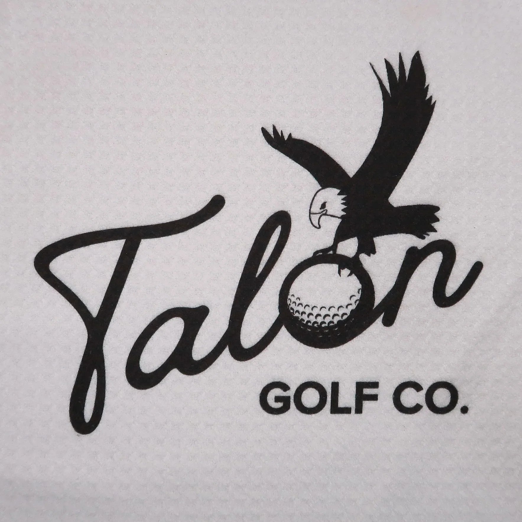 Talon Golf Co. logo with eagle clutching a golf ball on textured white fabric