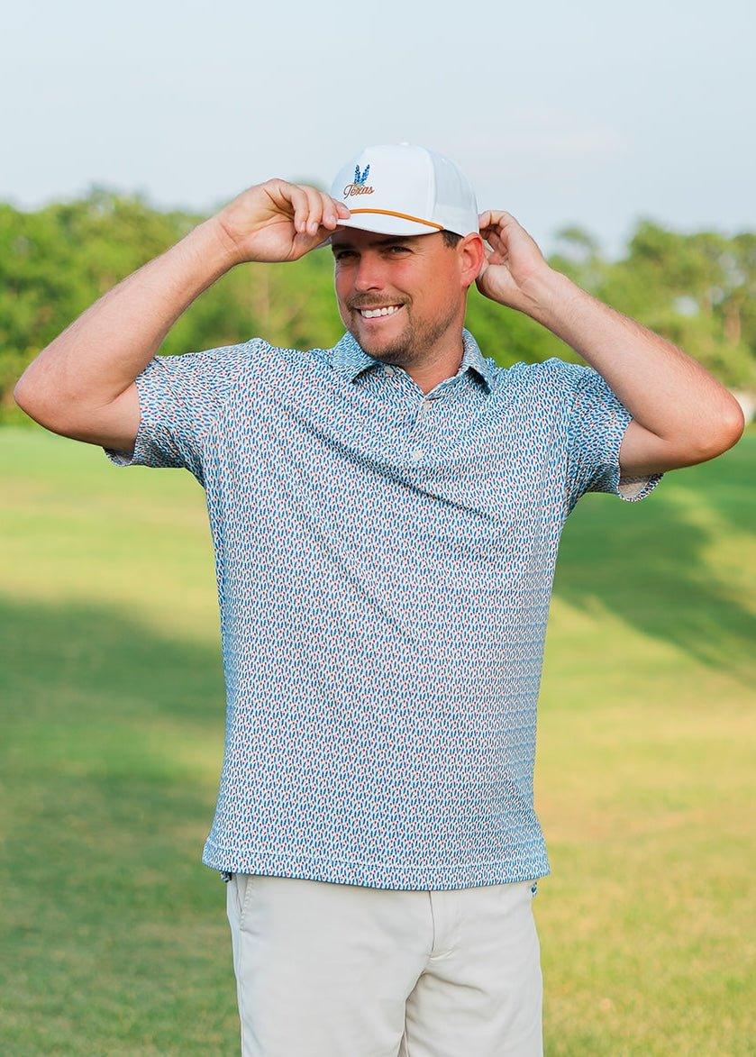 Smiling man outdoors wearing a patterned bluebonnet golf shirt and a white Texas hat