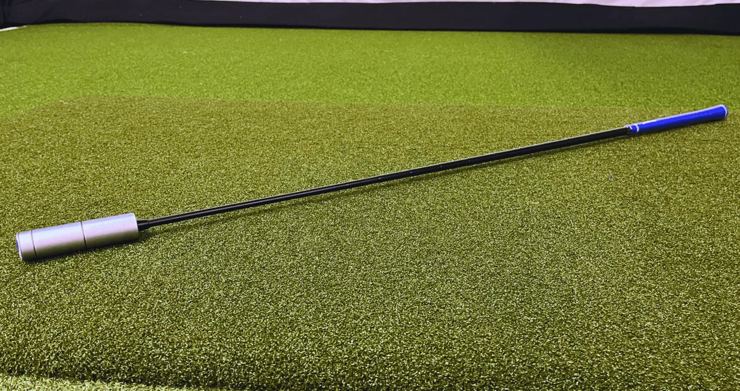 The Distance Builder golf training aid on green turf with a blue grip and silver weighted end