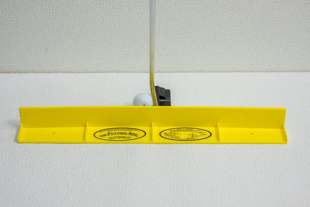Yellow Putting Arc golf training aid aligned with putter and golf ball on white textured surface
