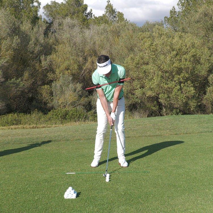 Golfer practicing putting stroke alignment on green with golf balls and alignment rods in outdoor setting