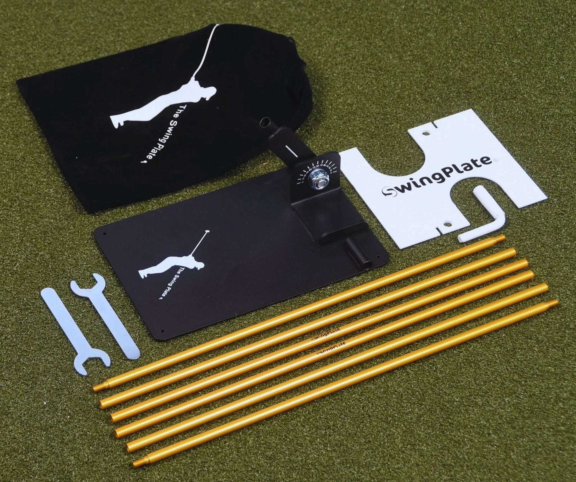 Swing Plate golf training device parts including base, orange rods, tools, and storage bag on green turf