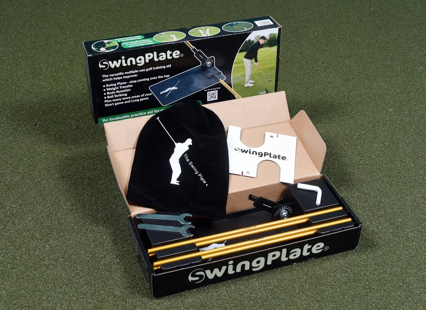 SwingPlate golf training aid kit with box, golden rods, black velvet cover, wrenches, and instructional card on green surface