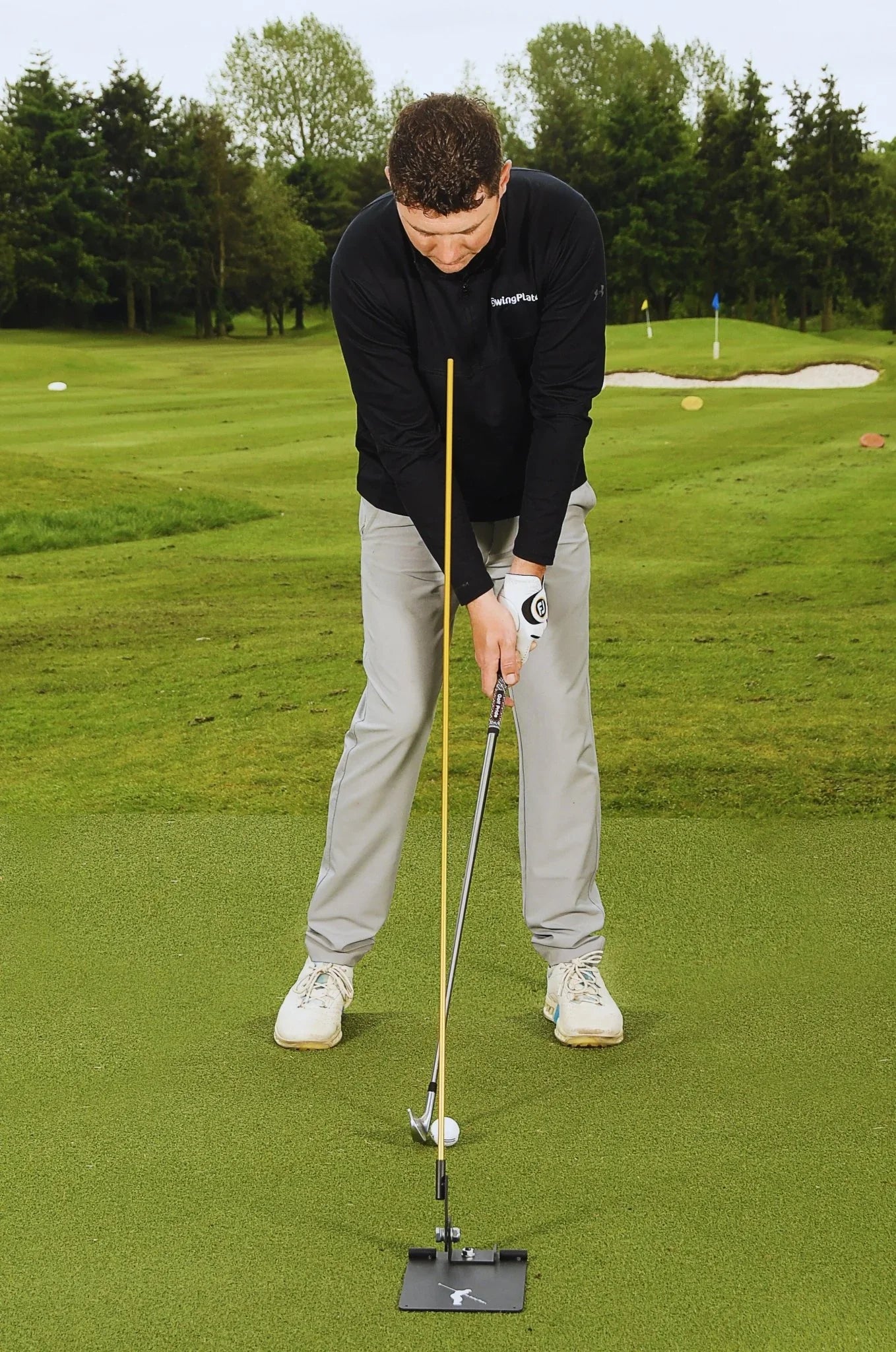 Golfer on putting green practicing with SwingPlate golf training aid and golf club