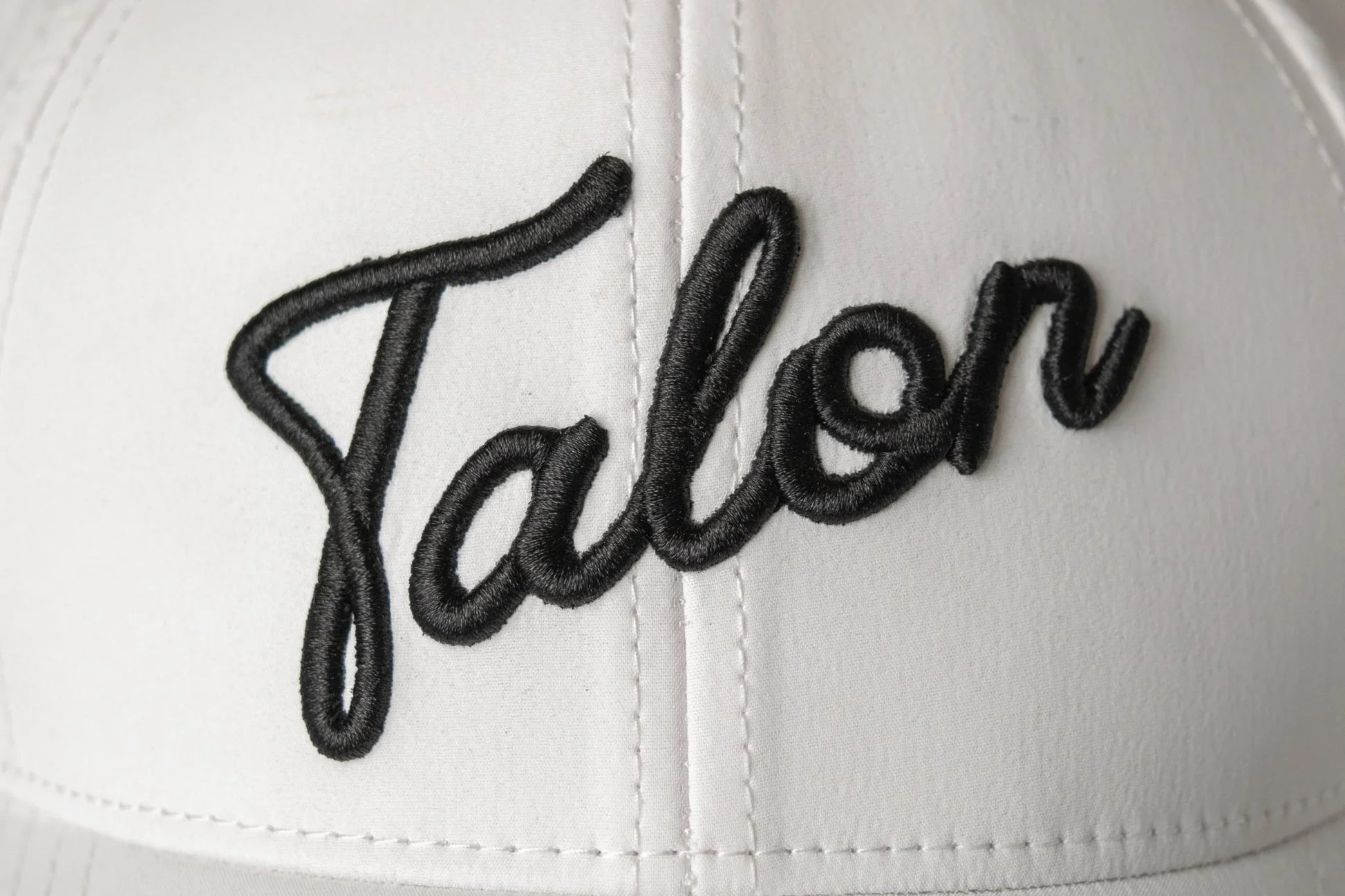 Close-up of white cap with black embroidered word 'Ralen' in script font